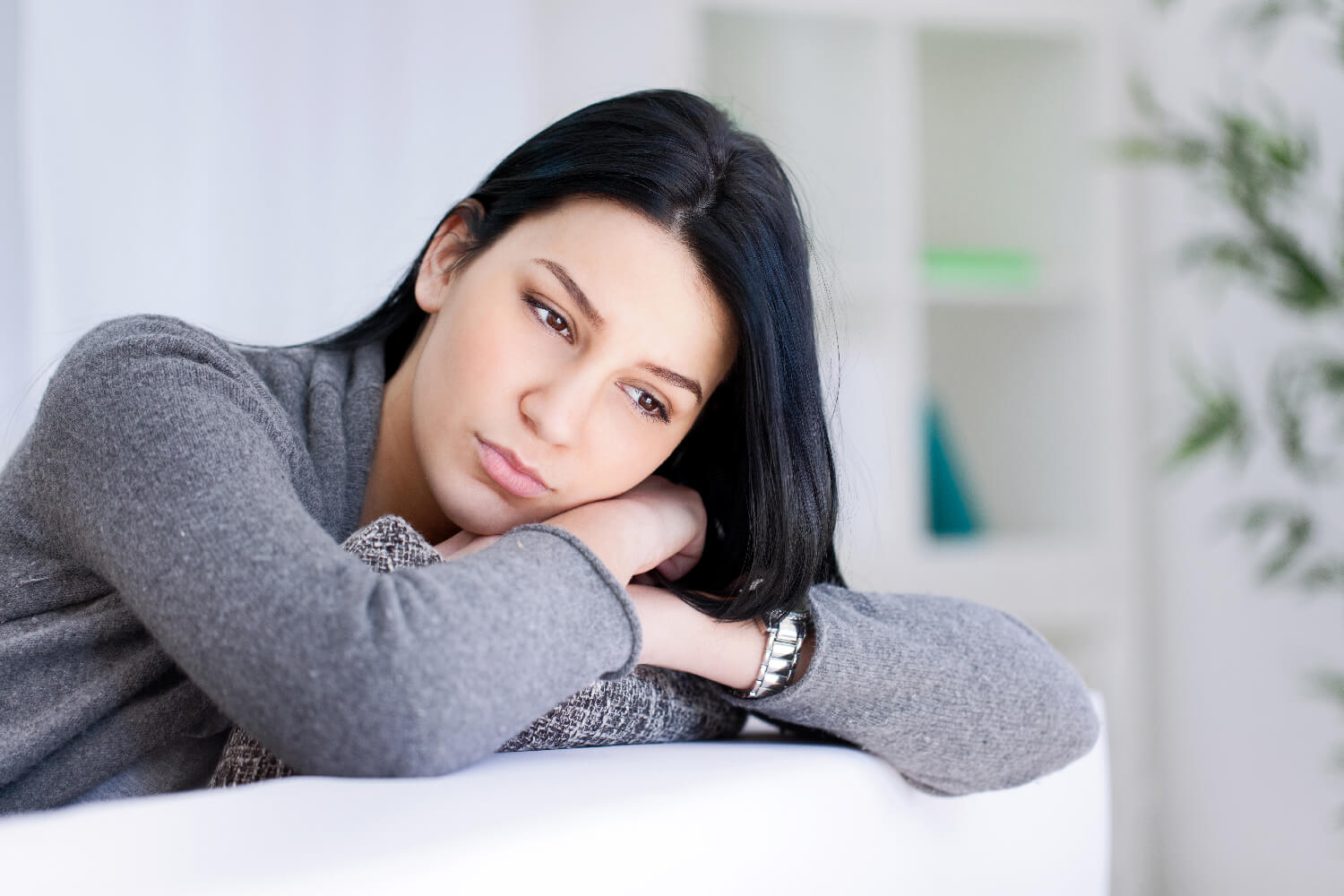 Woman leaning on a couch sad 