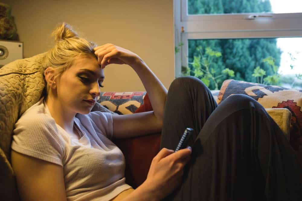 Woman using phone while learning about long-term effects of Vyvanse at home